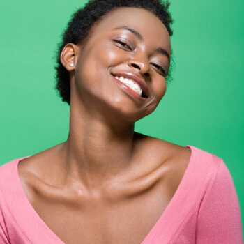 A young black woman smiling against a green background.