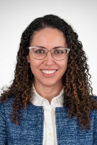 A woman with curly hair wearing glasses.