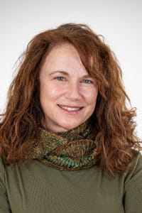 A woman wearing a green sweater and a green scarf.